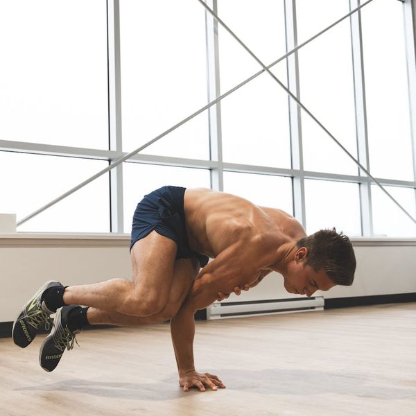 Man performing a controlled strength exercise in a modern, dark gym environment.